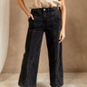 Lower body front view of female model wearing the Wyatt Black Denim Braided Jeans that have washed black denim, wide legs, and a braided waistband. Worn with beige top.