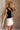 Side view of female model wearing the Sasha Black Bow Sweater Tank, paired with a white skirt.