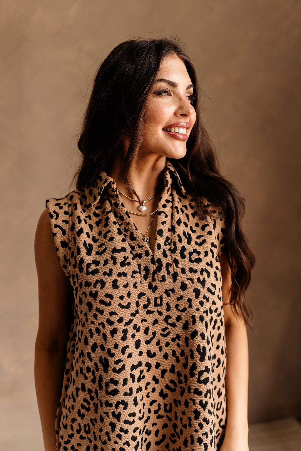 Upper body front view of model wearing the Ashley Leopard Print Mini Dress that is brown with black animal print, a collar, and is sleeveless.