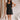 Full body front view of female model wearing the Peyton Denim Zip Front Mini Dress in black, that has washed black denim fabric, a gold front zipper, straps with buckle adjustments, and pockets.