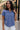 Upper body front view of female model wearing the Leah Blue Short Sleeve T-Shirt, paired with white shorts.