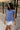 Side view of female model wearing the Leah Blue Short Sleeve T-Shirt, paired with white shorts.