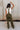 Full body back view of female model wearing the Kimberly Olive Green Jumpsuit, worn over a white shirt.