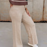 Lower body side view of female model wearing the Aurora Beige Knit Pants, paired with striped top.