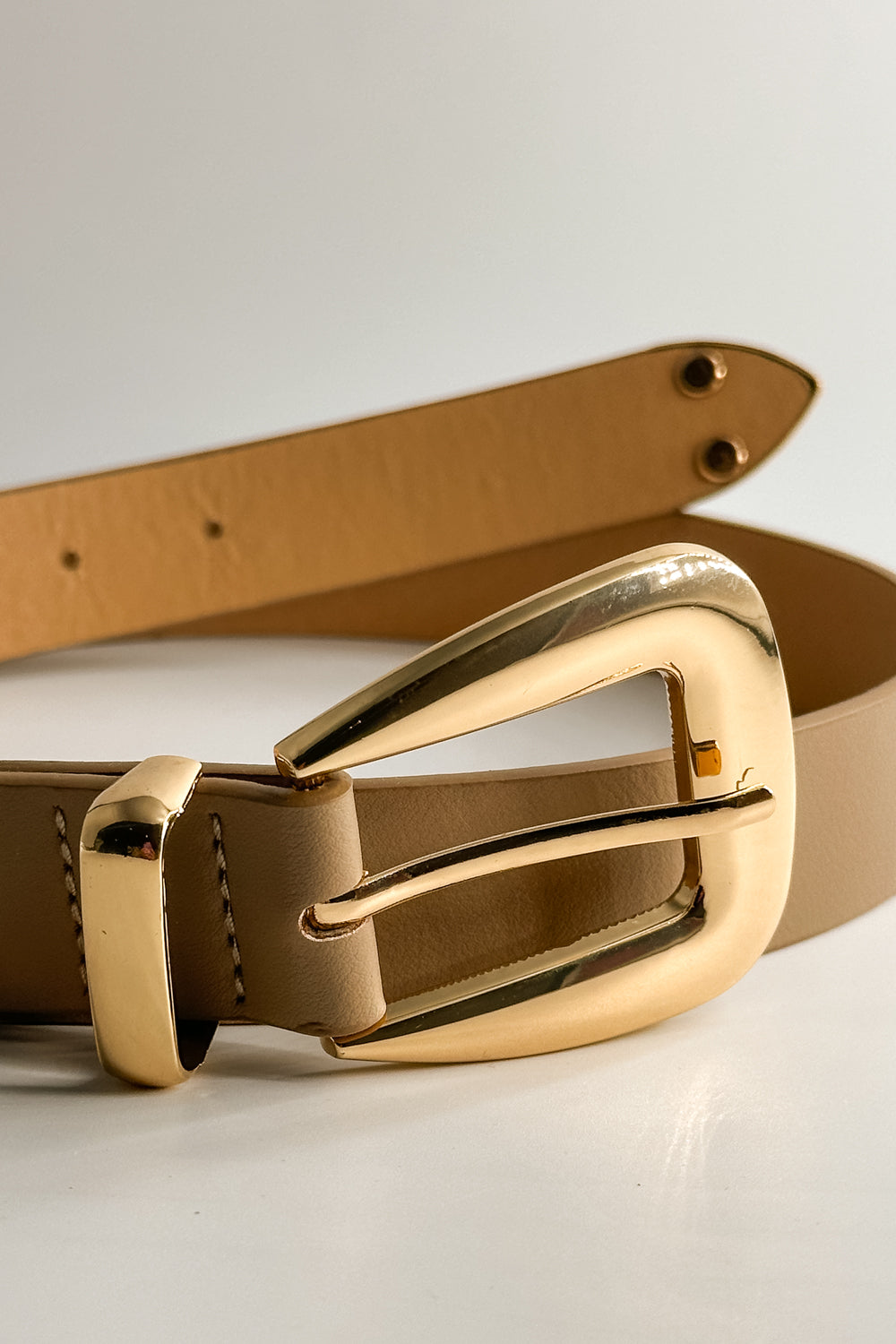 Close up view of the Lucia Taupe Western Adjustable Belt which features aupe Leather Fabric, Gold Adjustable Buckle and Gold Western Detail