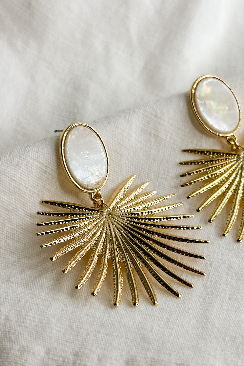 Flat lay view of the Penelope Gold & Opal Starburst Dangle Earring which features Gold stabrust earrings with opal stone design