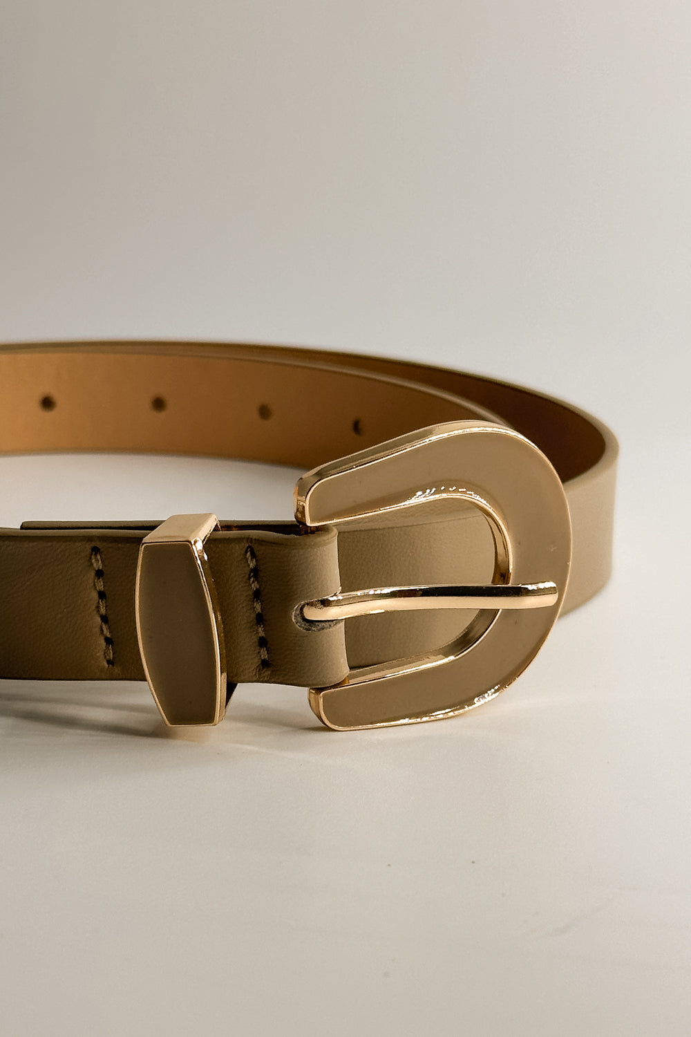 Close up front view of the Irene Taupe Slim Adjustable Belt which features Taupe Leather Fabric and Gold Adjustable Buckle