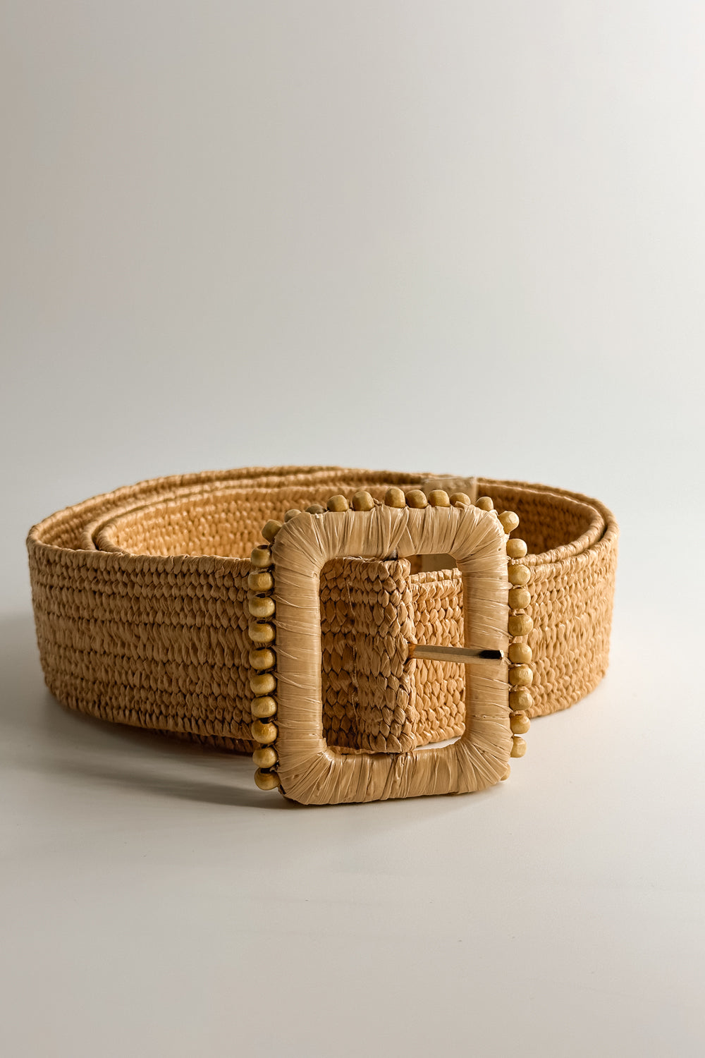 Front view of the Lyla Tan Rattan Beaded Belt which features Tan Woven Fabric and Tan Rattan Adjustable Buckle with Wooden Bead Details