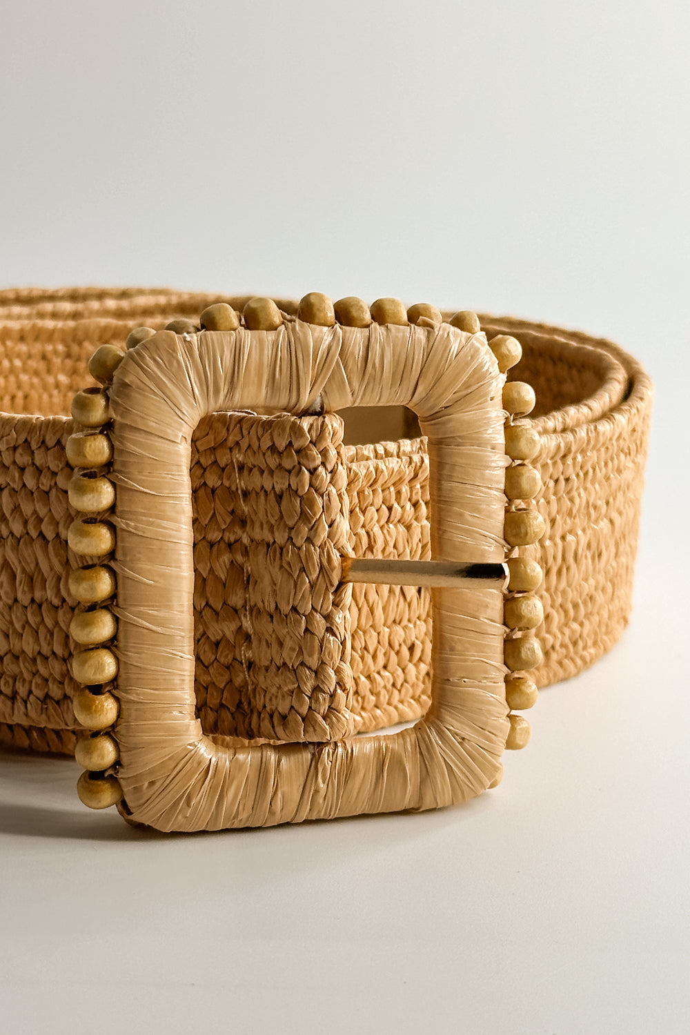 Close up view of the Lyla Tan Rattan Beaded Belt which features Tan Woven Fabric and Tan Rattan Adjustable Buckle with Wooden Bead Details