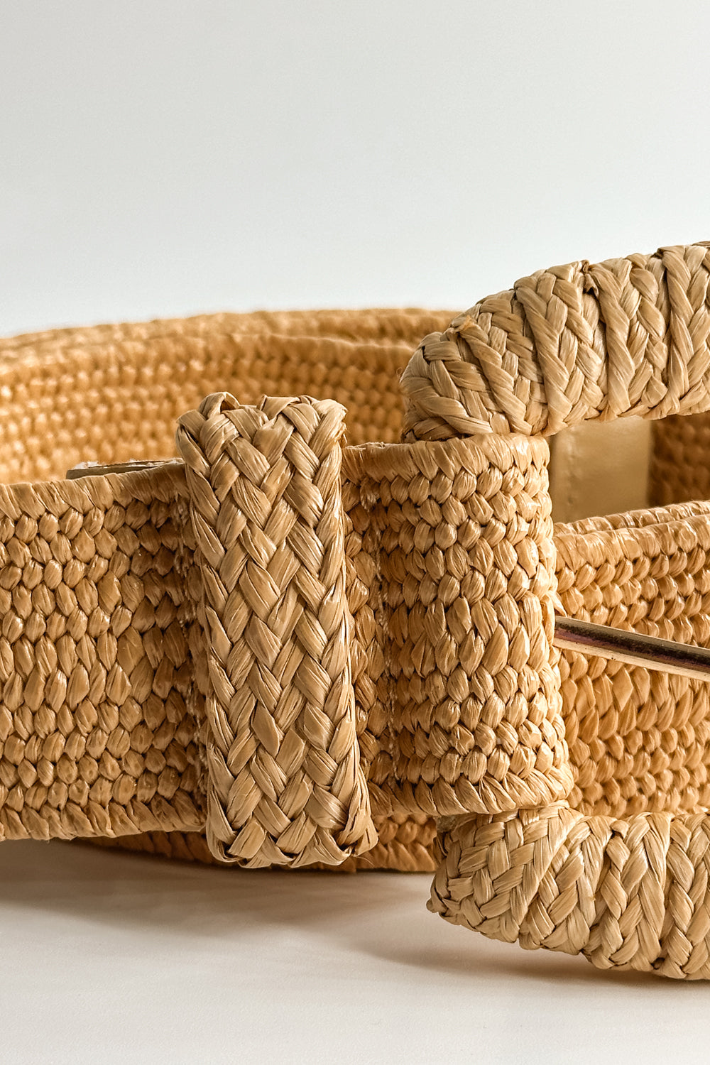 Close up view of the Nova Light Tan Rattan Belt which features khaki rattan fabric, monochrome rattan covered adjustable buckle