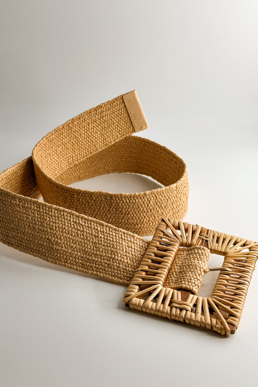 Flat lay view of the Savannah Tan Rattan Square Adjustable Belt which features tan rattan fabric, square rattan adjustable buckle