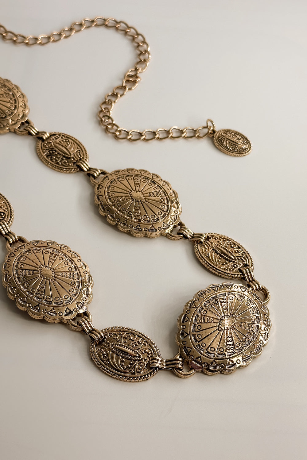 Flat lay view of the Melody Gold Medallion Chain Belt which features Gold Metal Medallions and Adjustable Chain Link 
