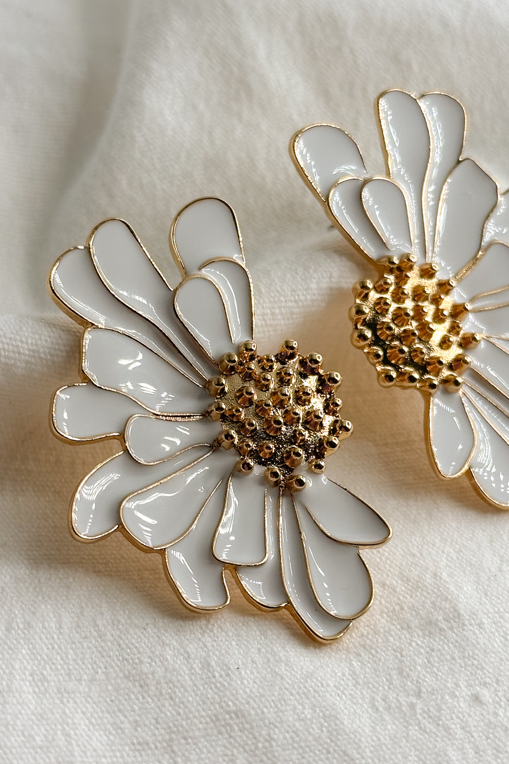 Close up view of the Chloe White & Gold Flower Stud Earring which features oversized white flower studs with gold details