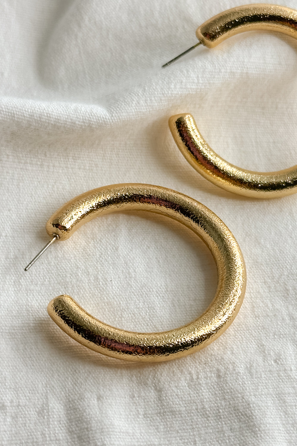 Flat lay view of the Angela Gold Open Hoops which features medoium, open gold hoops