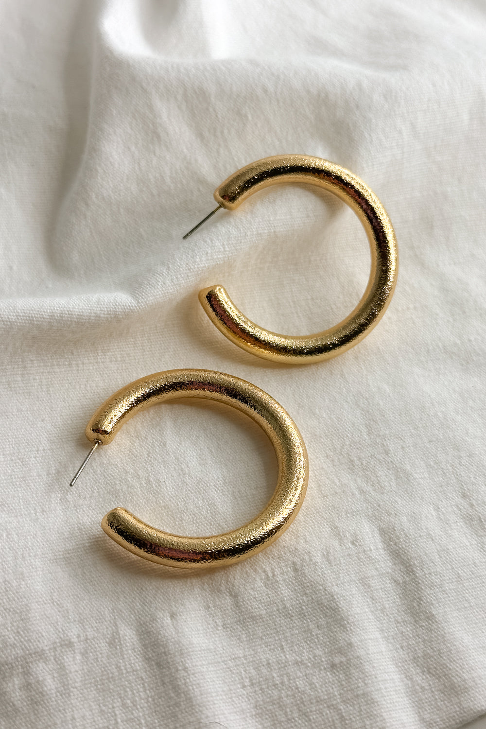 Flat lay view of the Angela Gold Open Hoops which features medoium, open gold hoops