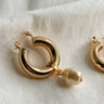 Flatt lay view of the Patricia Gold Hoop Pearl Dangle Earring which features Gold closed hoops with pearl dangle attachment
