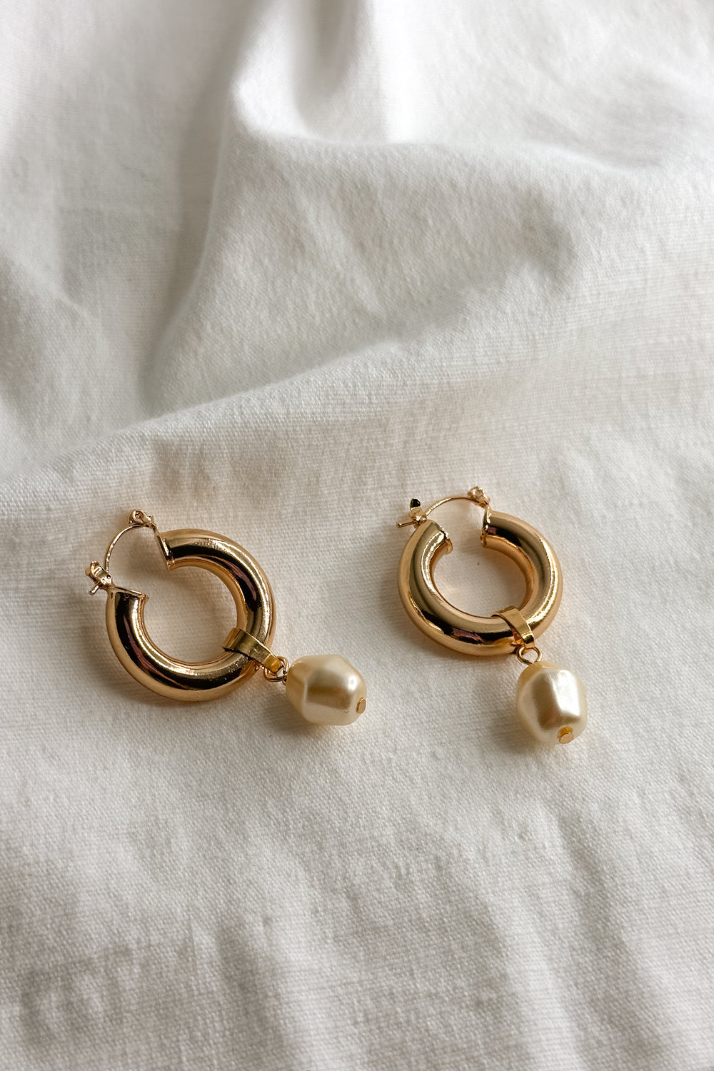 Flatt lay view of the Patricia Gold Hoop Pearl Dangle Earring which features Gold closed hoops with pearl dangle attachment