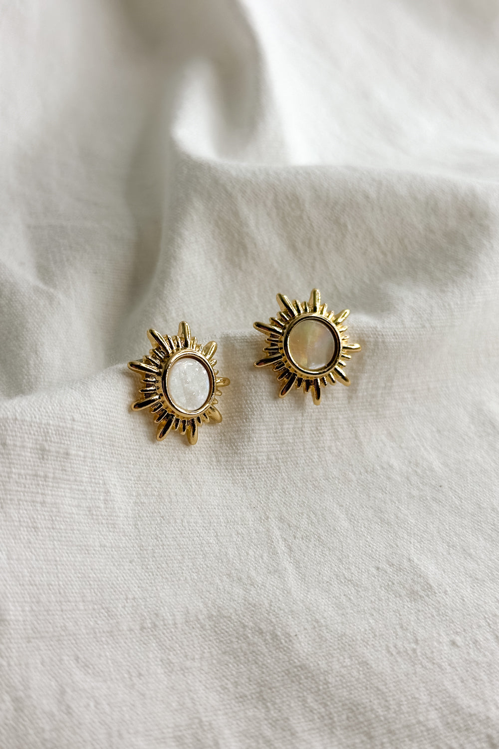 Close up flat lay view of Faith Gold & White Starburst Stud Earring which features old starburst studs with white stone