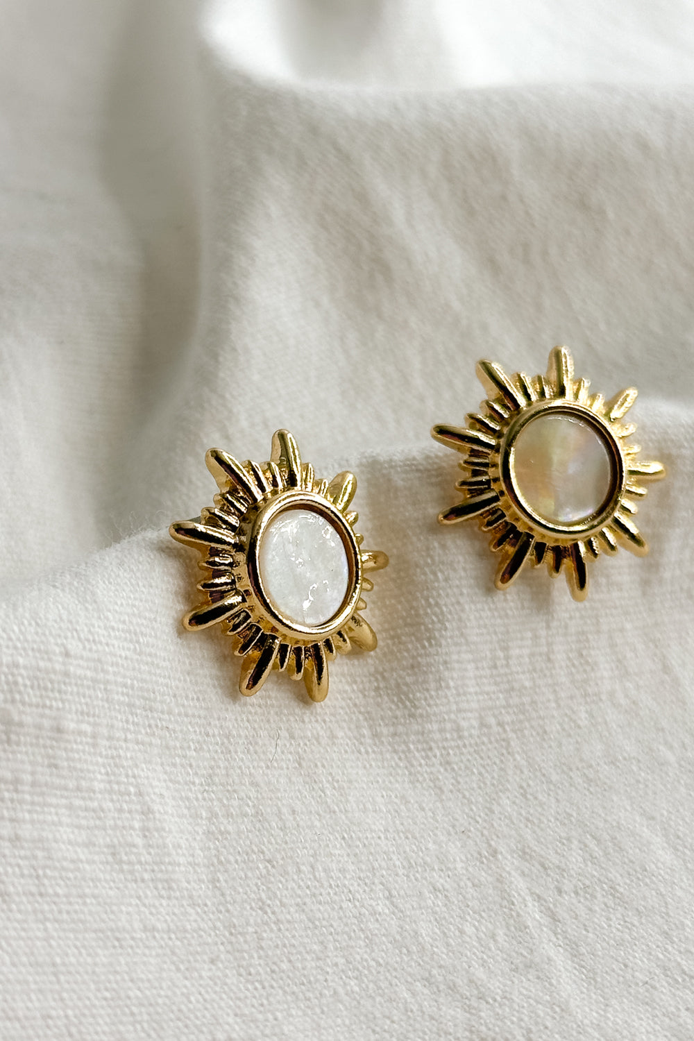 Close up flat lay view of Faith Gold & White Starburst Stud Earring which features old starburst studs with white stone