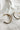 Close up flat lay view of the Jackie Gold & Black Woven Hoop Earring which features open, large gold hoops with black woven details