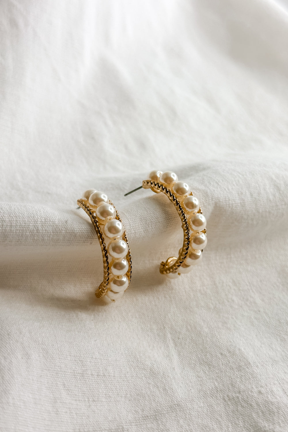 Flat lay view of the Elisa Gold Rope & Pearl Hoop Earring which features gold rope hoops with pearls