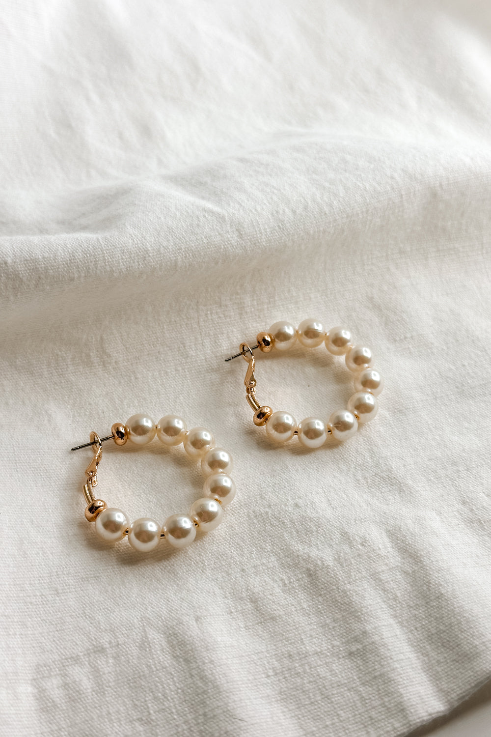 Close up view of the Irene Gold & Pearl Closed Hoop Earring which features gold closed hoops with pearls