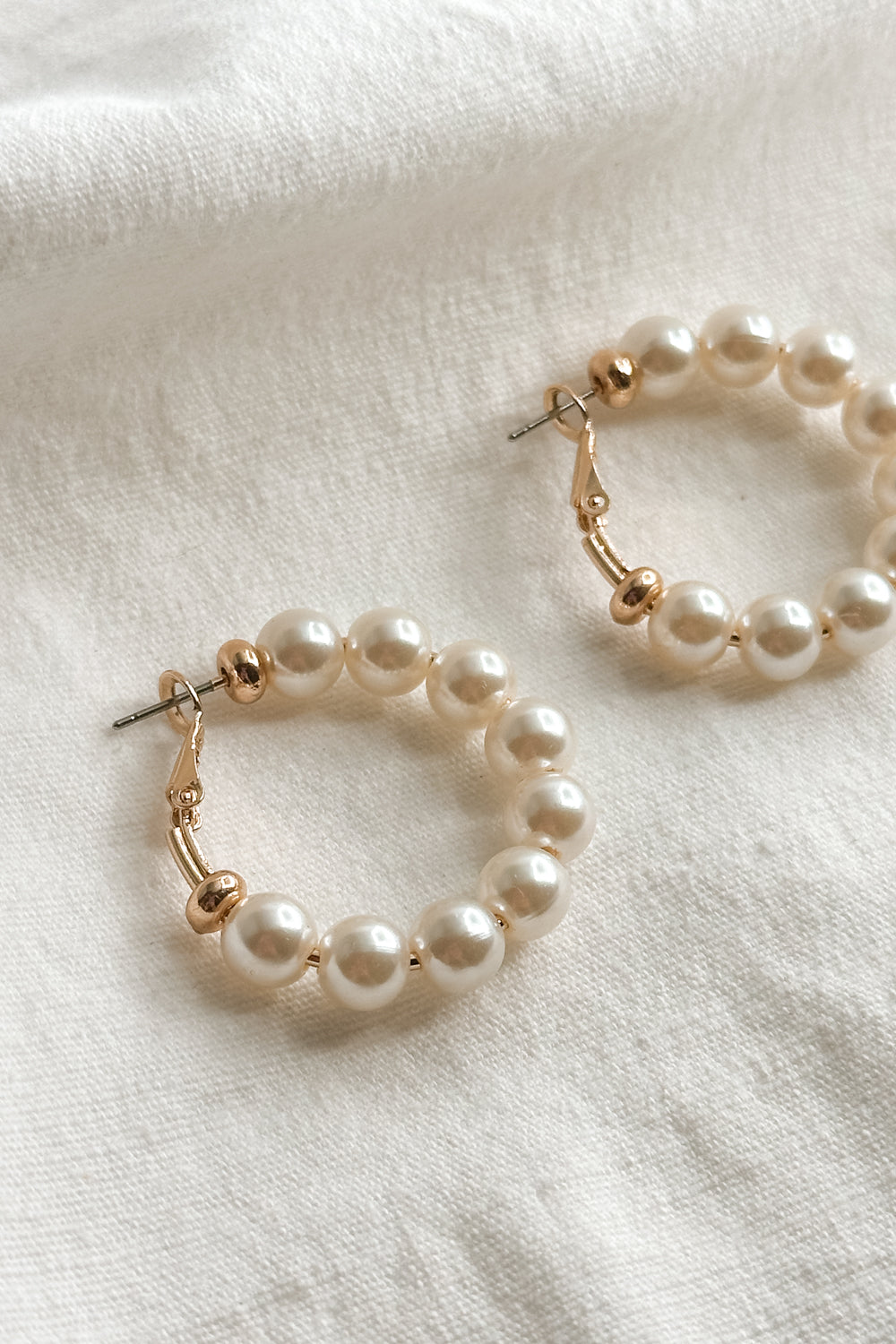 Close up view of the Irene Gold & Pearl Closed Hoop Earring which features gold closed hoops with pearls 