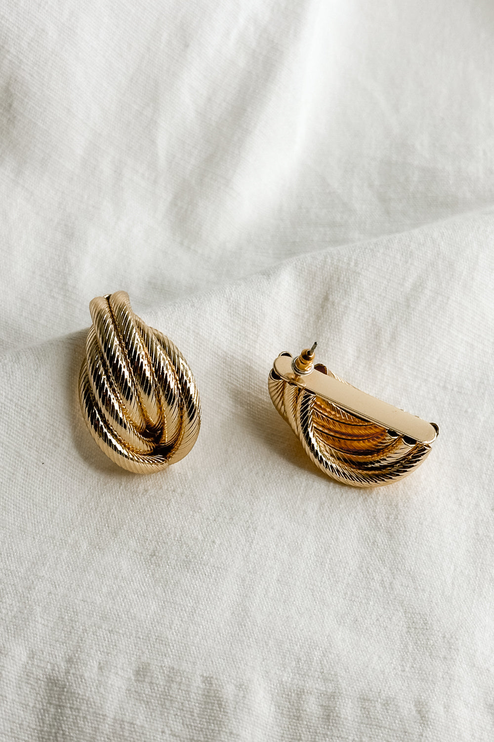 Flat lay view of the Stella Gold Rope Dangle Stud Earring which features oversized, gold rope studs