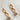 FLat lay view of the Rhodes Gold & Cream Chain Dangle Earring which features gold chain link dangle earrings with cream textured beads