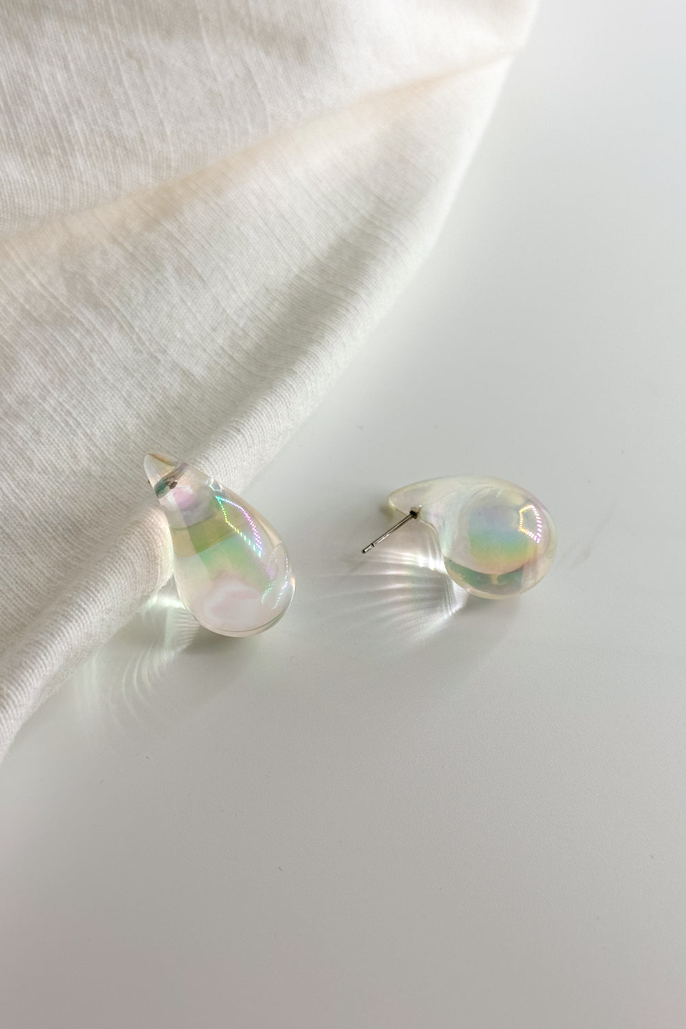 Flat lay view of the Mila Iridescent Scoop Teardrop Stud Earring which features iridescent teardrop studs