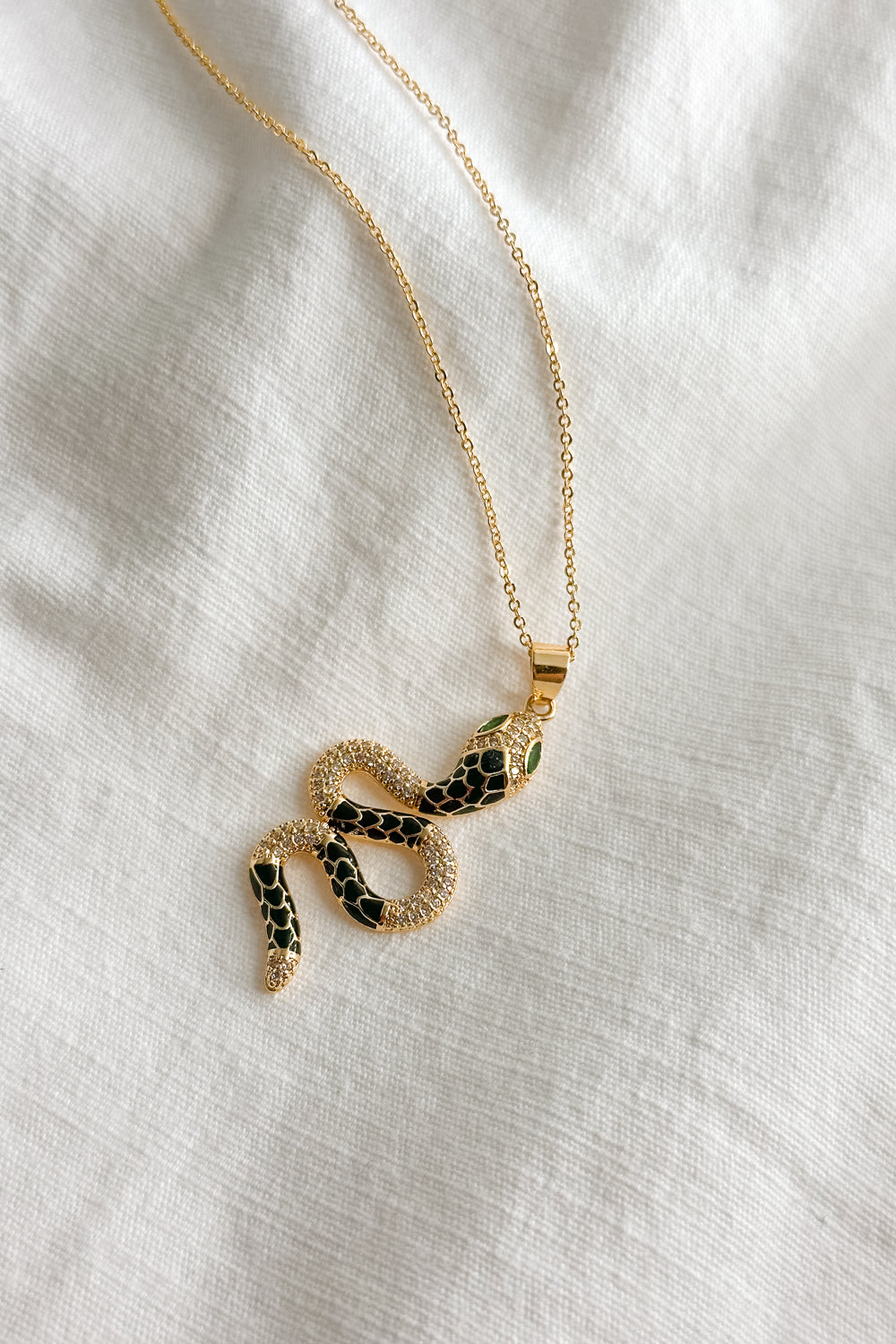 Flat lay view of the Lucia Black & Gold Snake Necklace which features gold chain link single layer with a black and gold snake medallion