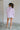 Full body back view of female model wearing the Madilyn Lavender High Neck Top which features Lavender Lightweight Fabric, High Neckline with Tie Closure and Short Sleeves
