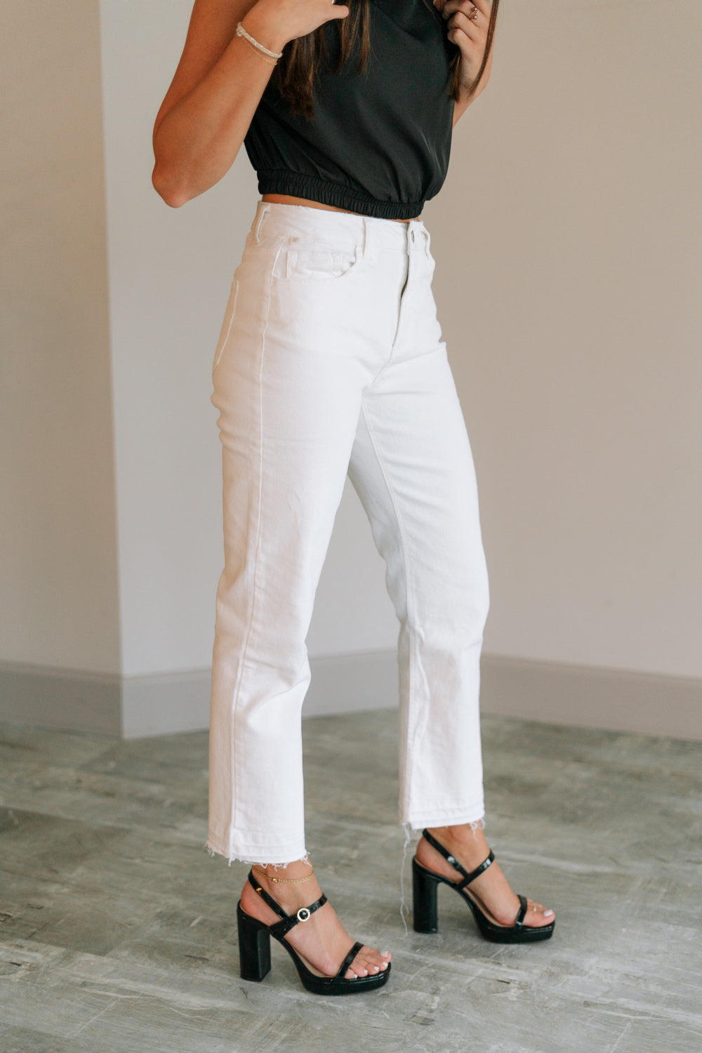 Side view of female model wearing the Ayla White Straight Leg Jeans White Denim Fabric, Straight Leg, Two Front Pockets, Two Back Pockets, Front Zipper with Button Closure and Fray Hem