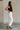 Side view of female model wearing the Ayla White Straight Leg Jeans White Denim Fabric, Straight Leg, Two Front Pockets, Two Back Pockets, Front Zipper with Button Closure and Fray Hem