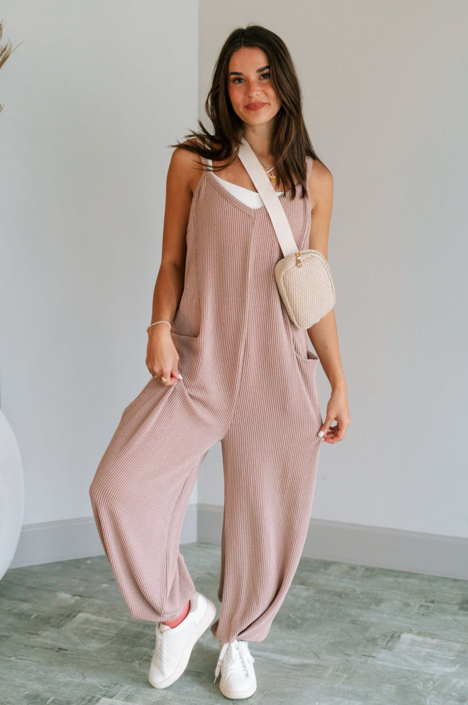 Full body view of female model wearing the Noelle Taupe Ribbed Sleeveless Jumpsuit which features Taupe Ribbed Fabric, Jogger Pant Legs, Two Side Pockets and V-Neckline