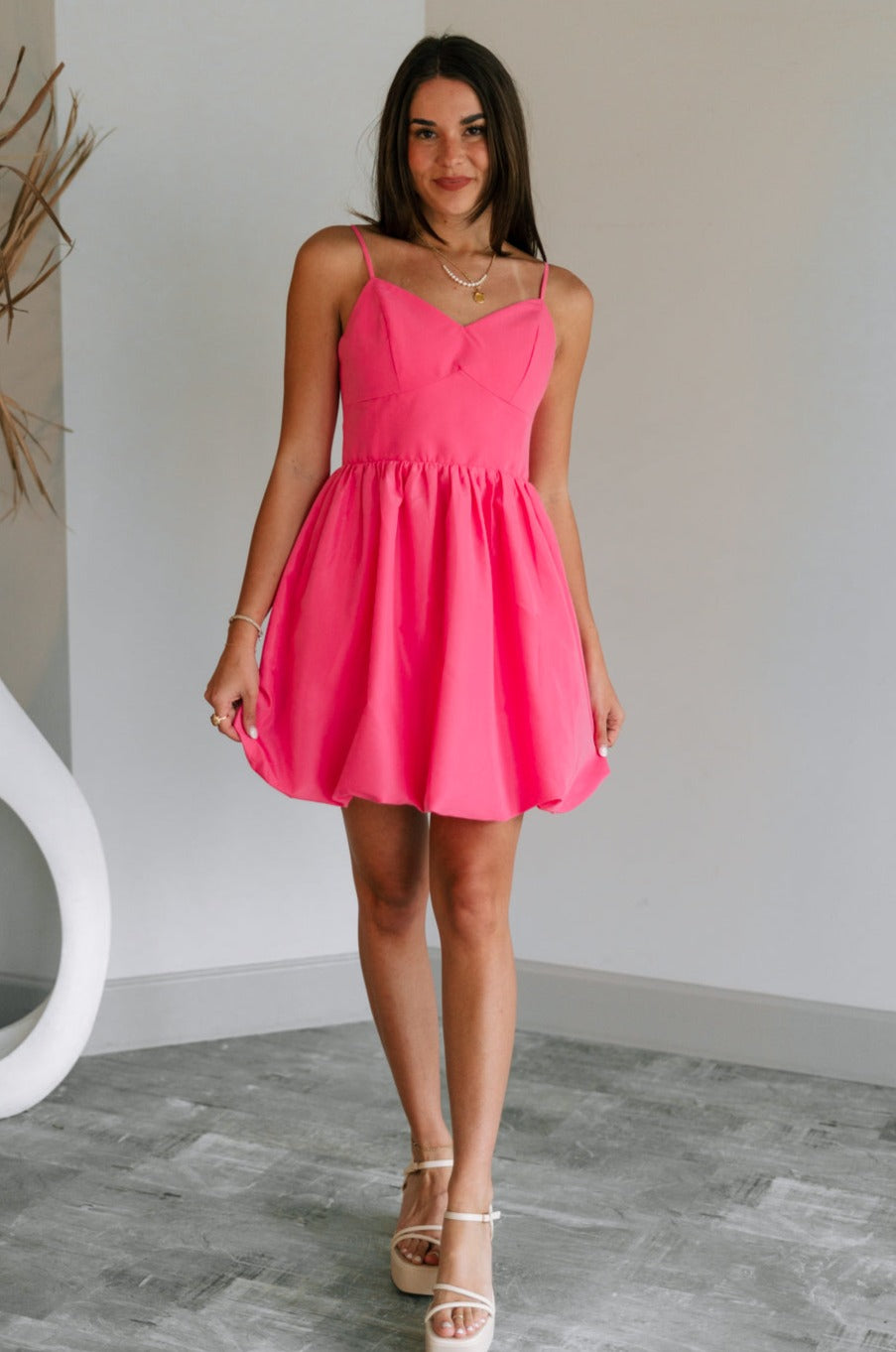 Full body view of female model wearing the Camila Sleeveless Bubble Mini Dress in PInk which features Lightweight Fabric, Mini Length with Bubble Hem, Two Side Slit Pockets, Sweetheart Neckline, Adjustable Straps and Smocked Back