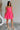 Full body side view of female model wearing the Camila Sleeveless Bubble Mini Dress in PInk which features Lightweight Fabric, Mini Length with Bubble Hem, Two Side Slit Pockets, Sweetheart Neckline, Adjustable Straps and Smocked Back