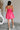 Full body back view of female model wearing the Camila Sleeveless Bubble Mini Dress in PInk which features Lightweight Fabric, Mini Length with Bubble Hem, Two Side Slit Pockets, Sweetheart Neckline, Adjustable Straps and Smocked Back