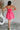 Full body back view of female model wearing the Camila Sleeveless Bubble Mini Dress in PInk which features Lightweight Fabric, Mini Length with Bubble Hem, Two Side Slit Pockets, Sweetheart Neckline, Adjustable Straps and Smocked Back