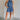 Full body view of female model wearing the Leila Dark Blue Halter Neckline Romper which features Grey Blue Textured Fabric, Two Side Slit Pockets, Halter Neckline with Tie,  Elastic Waistband and Back Key Hole