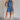 Full body view of female model wearing the Leila Dark Blue Halter Neckline Romper which features Grey Blue Textured Fabric, Two Side Slit Pockets, Halter Neckline with Tie,  Elastic Waistband and Back Key Hole