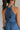 Back view of female model wearing the Leila Dark Blue Halter Neckline Romper which features Grey Blue Textured Fabric, Two Side Slit Pockets, Halter Neckline with Tie, Elastic Waistband and Back Key Hole