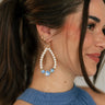 SIde view of female model wearing the Sienna White & Blue Pearl Dangle Earring which features  teardrop, dangle earrings with white pearls and blue design beads
