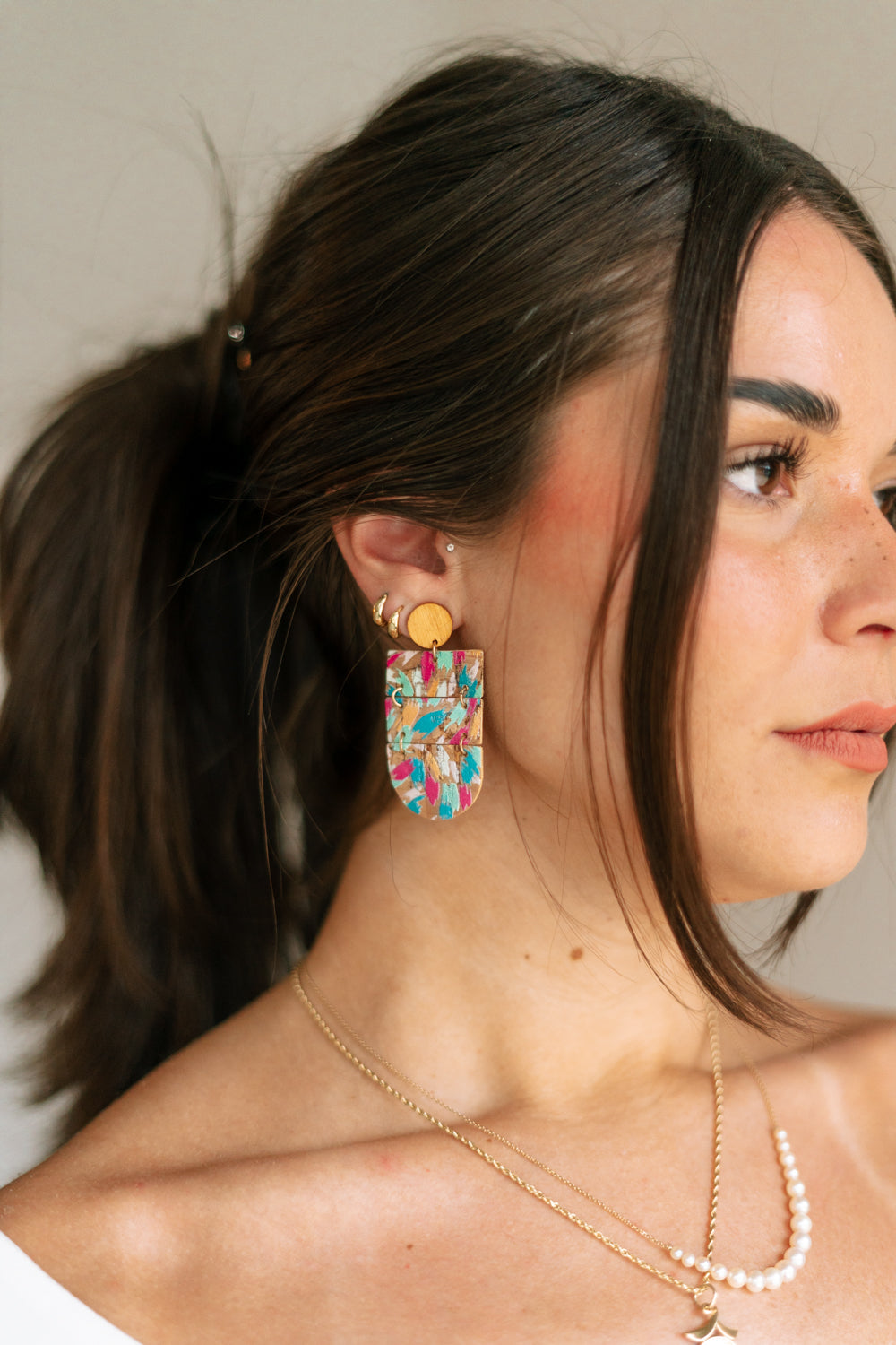 Side view of female model wearing the Julia Cork Multi Dangle Earring which features cork dangle earrings with multi color spots design
