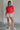 Full body view of female model wearing the Evie Red Coral Short Sleeve Top which features Coral Red Cotton Fabric, Cropped Waist with Raw Hem, Round Neckline and Short Sleeves
