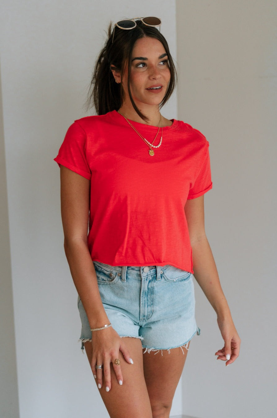 Front view of female model wearing the Evie Red Coral Short Sleeve Top which features Coral Red Cotton Fabric, Cropped Waist with Raw Hem, Round Neckline and Short Sleeves