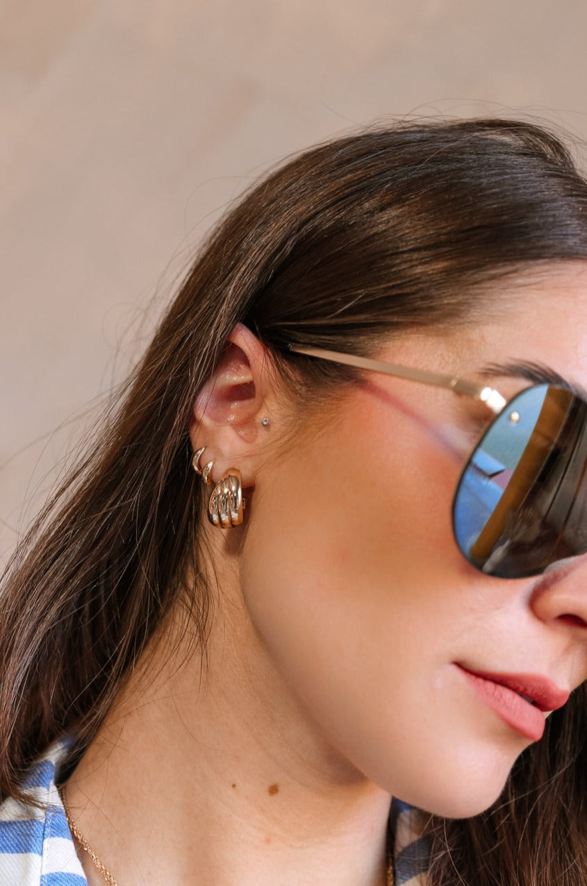 Side view of female model's face; model is wearing the Evelyn Layered Gold Hoop Earring that feature 3 small gold hoops attached together.