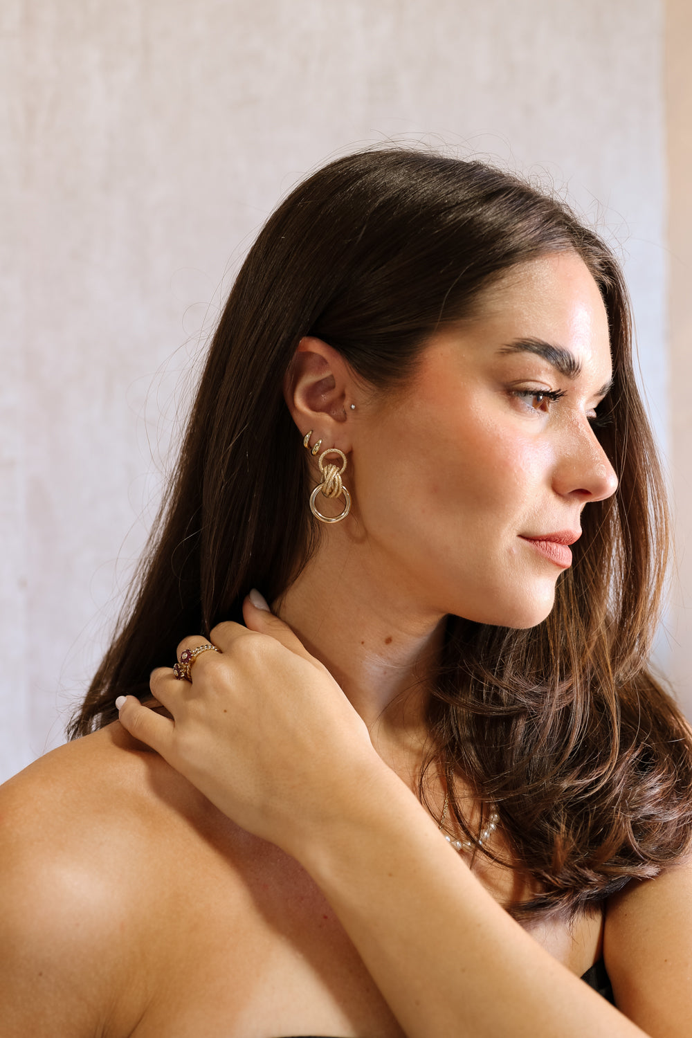 Side view of female model wearing the Lizzie Gold Circle Dangle Earrings that have matt and sparkly gold circles linked together.