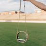 Model's hand is showing holding the Bianca Clear & Gold Round Purse against grass background.