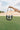 Image shows model's hand holding the Margaret Clear & Black Purse in front of grass field.